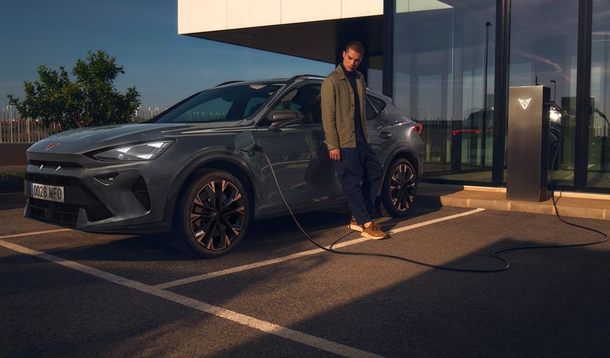 Man leunt tegen CUPRA Formentor aan naast laadpaal