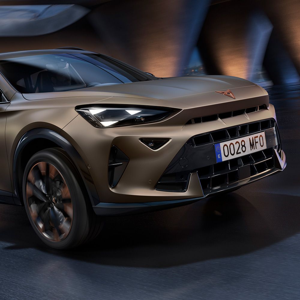 Close-up van de voorkant van een nieuwe century bronze 2024 CUPRA Formentor CUV met koperen accentwielen, kenmerkende driehoekige voorlichten en het onderscheidende CUPRA-logo.