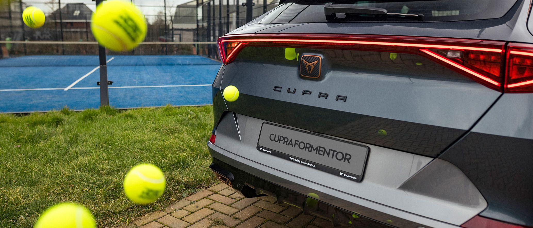 CUPRA Formentor met daaromheen padelballen, met op de achtergrond een padelbaan